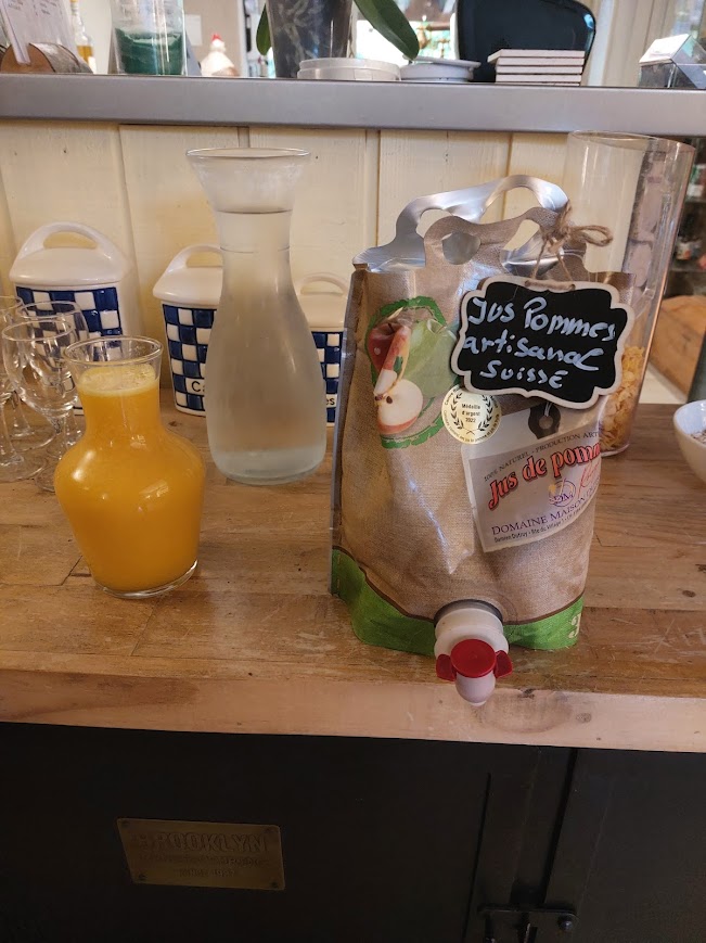 Pont en pierre, terrasse de restaurant provençale Petit pont de pierre sèche et moellons au-dessus d'un canal d'eau, menant à une terrasse de restaurant avec tables sous une structure en bois à toiture de tuiles.