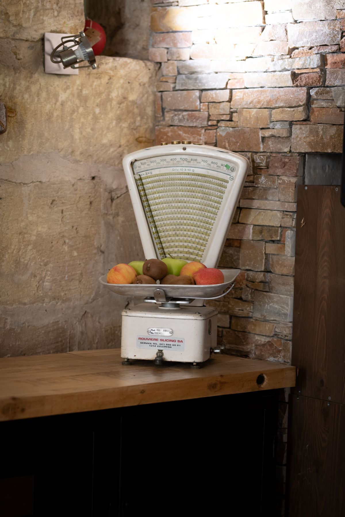 Pont en pierre, terrasse de restaurant provençale Petit pont de pierre sèche et moellons au-dessus d'un canal d'eau, menant à une terrasse de restaurant avec tables sous une structure en bois à toiture de tuiles.
