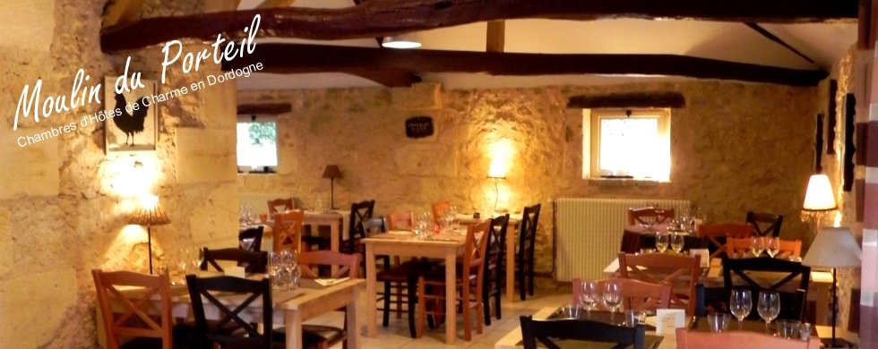 Pont en pierre, terrasse de restaurant provençale Petit pont de pierre sèche et moellons au-dessus d'un canal d'eau, menant à une terrasse de restaurant avec tables sous une structure en bois à toiture de tuiles.